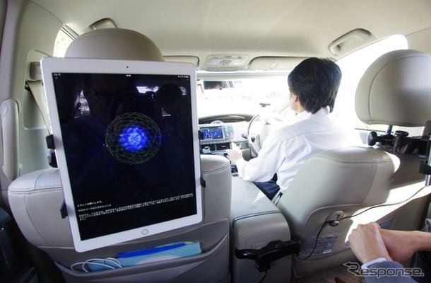 iPadのアプリとして稼働している「cocoro Drive」。色の付いた球体と、その回りのワイヤーフレームが感情を表現している。運転手は自動運転中だ。　《撮影　山田正昭》