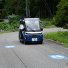 市道を走る「奥永源寺けい流カー」。道路上の黒い線が自動運転を制御するために敷設された電磁誘導線