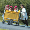 複数の子供が乗っていているカートを、坂道でも楽に操作できる「電動アシストお散歩カー」